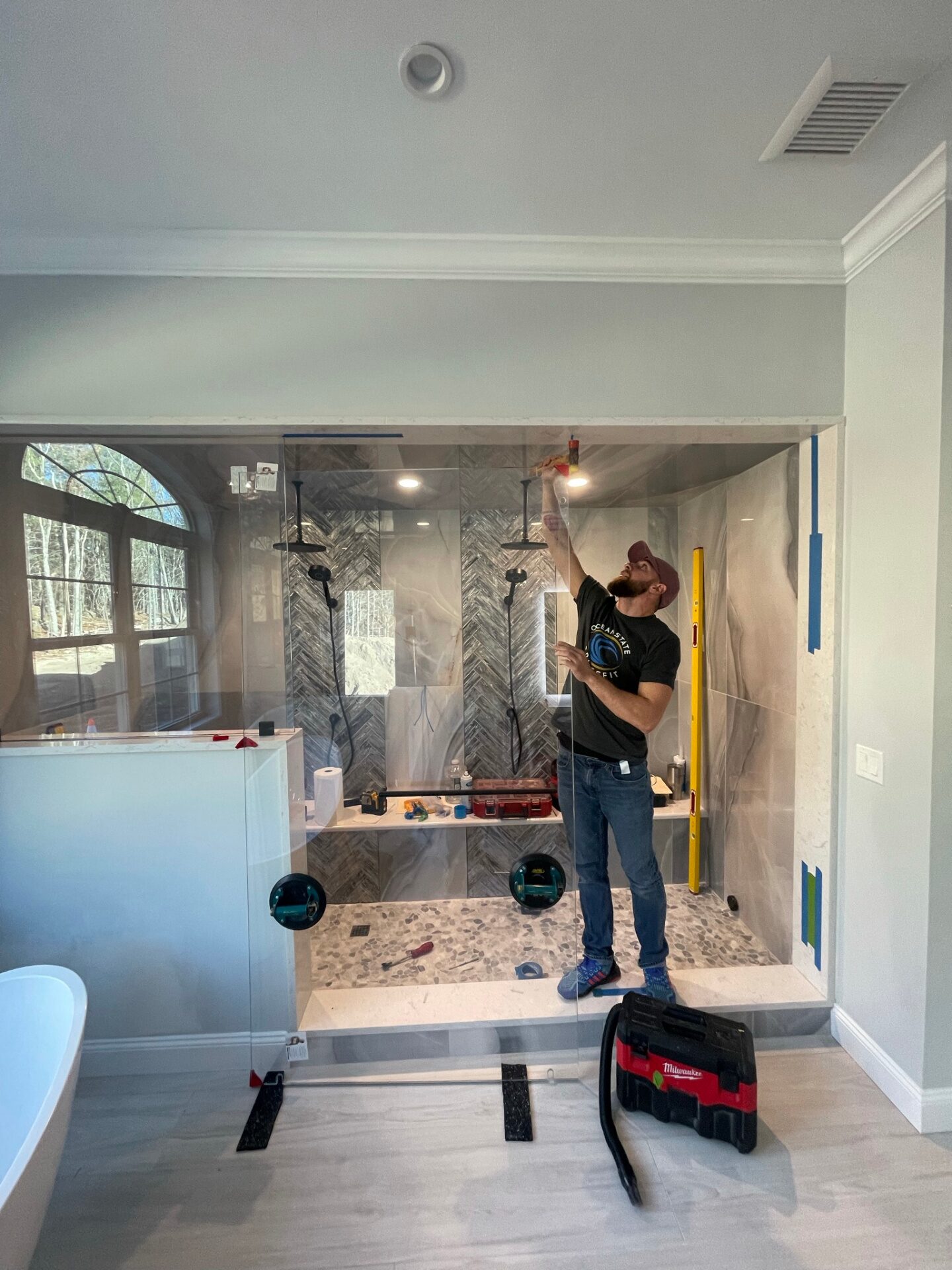 Grand Glasswork technician installing a custom glass shower panel on site